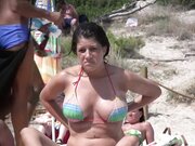 Hot babe with big breasts filmed at the beach topless