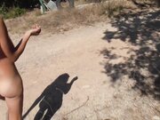 Exhibitionist nudist woman walking on road close to the beach